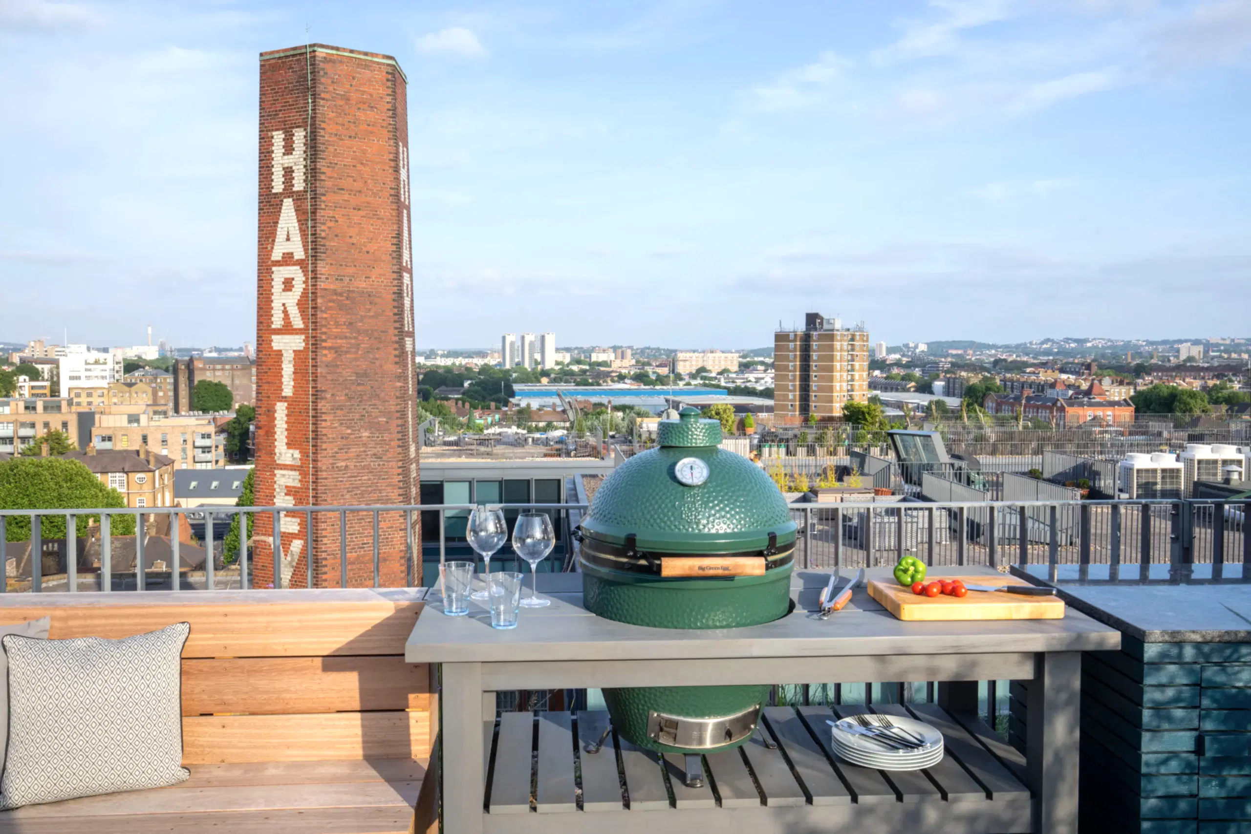 a grill on a table with wine glasses and a brick tower in the background