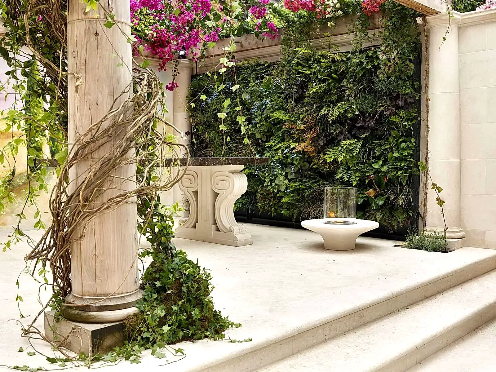 a stone patio with a fire pit and plants