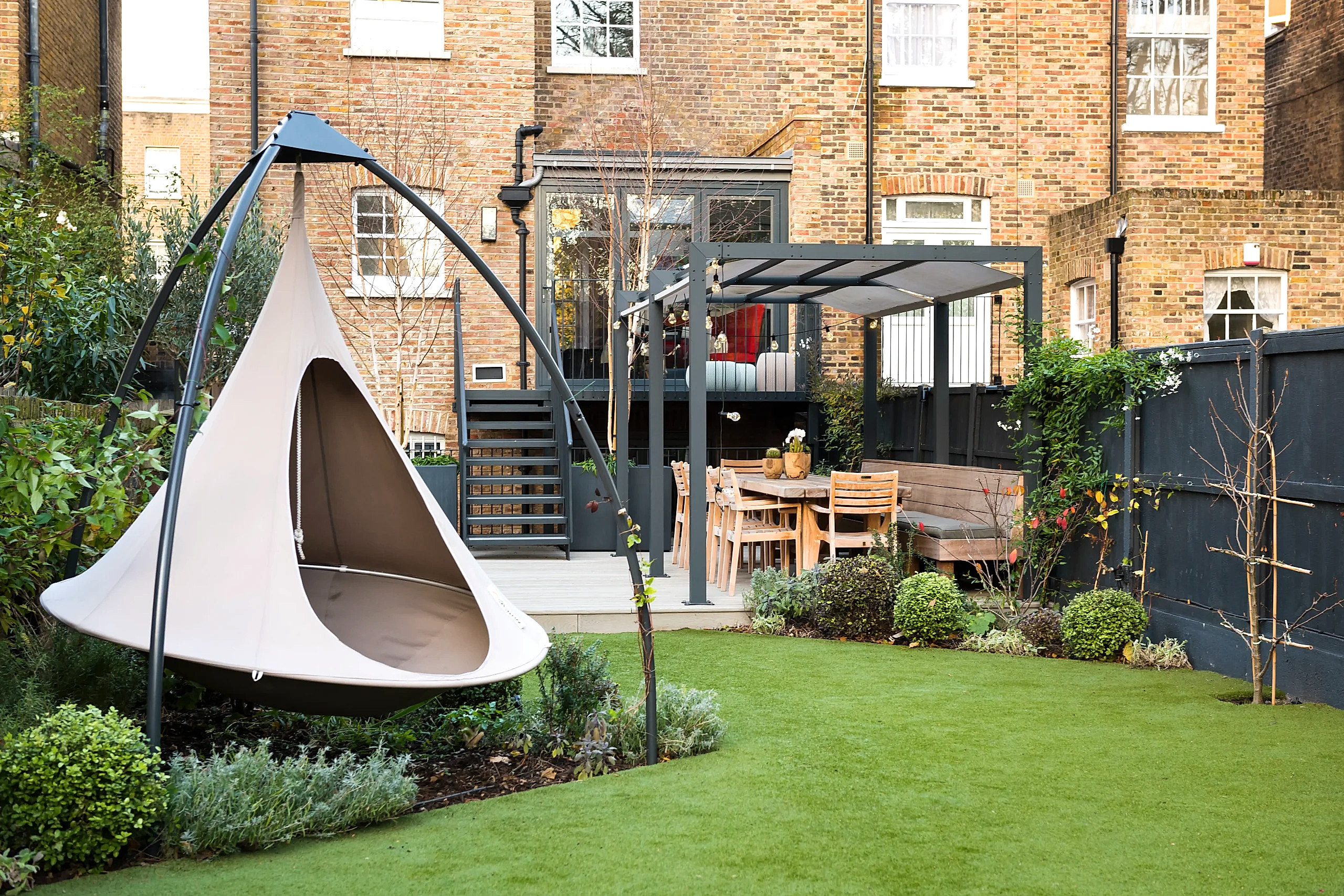 a hammock in a long thin garden with a pergola