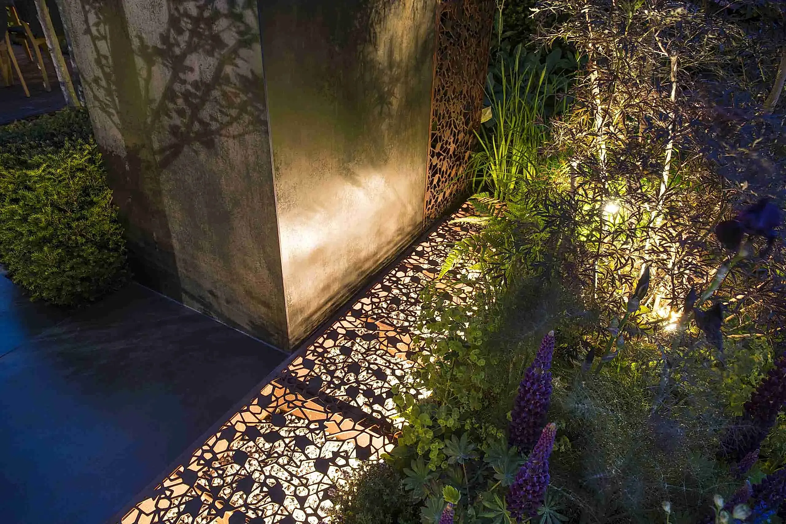 a lit up wall with plants and a metal structure