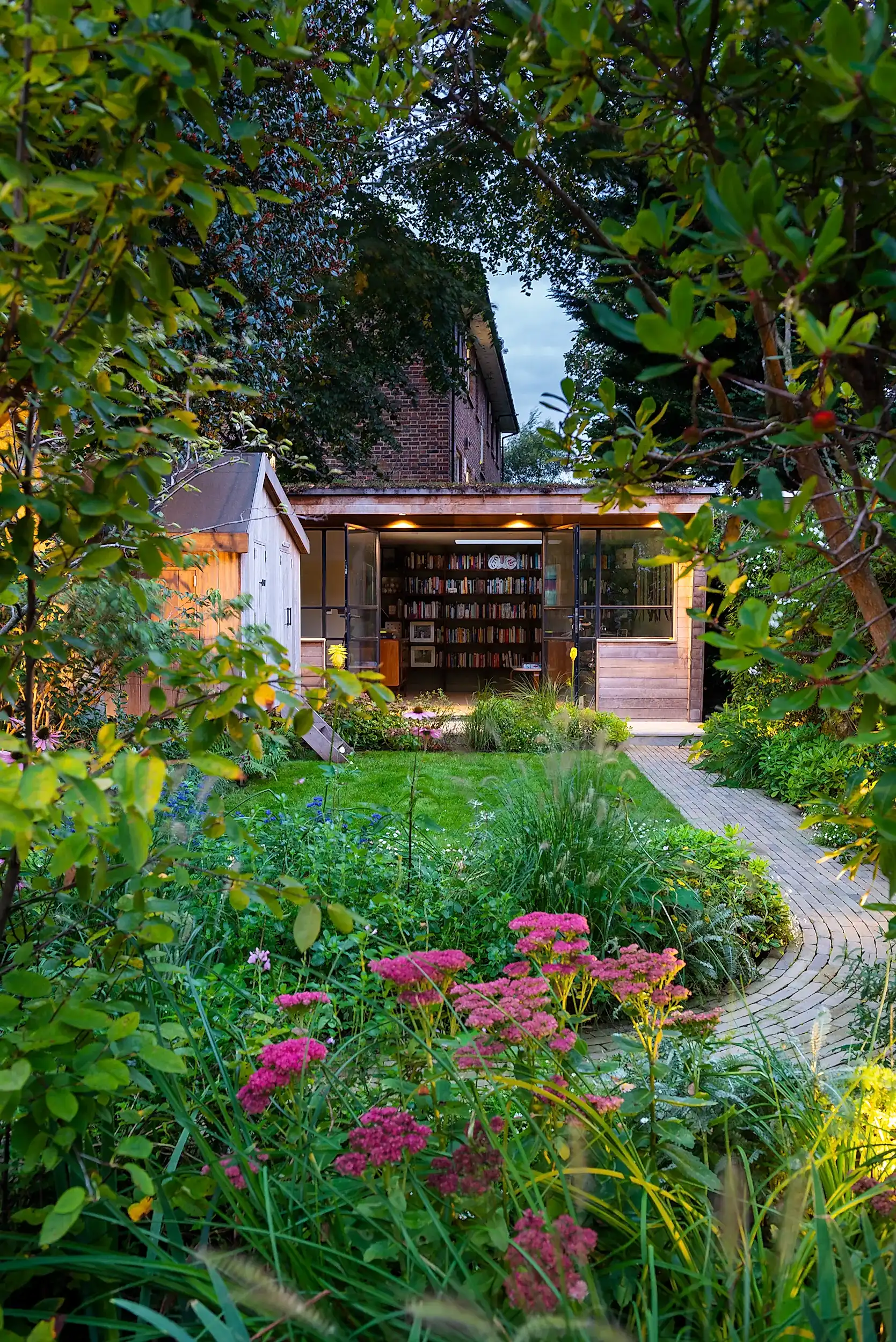 a long thin garden with a brick walkway and a building