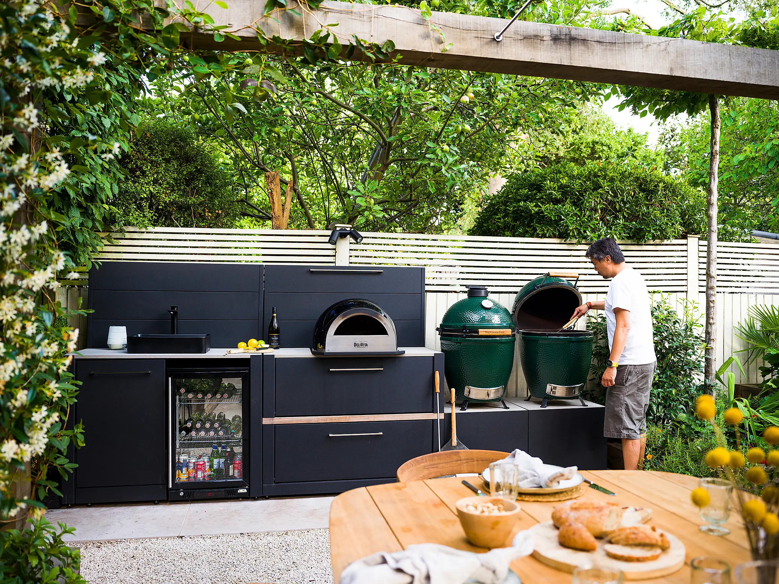 Outdoor kitchen with pizza oven, big green egg, fridge and pergola