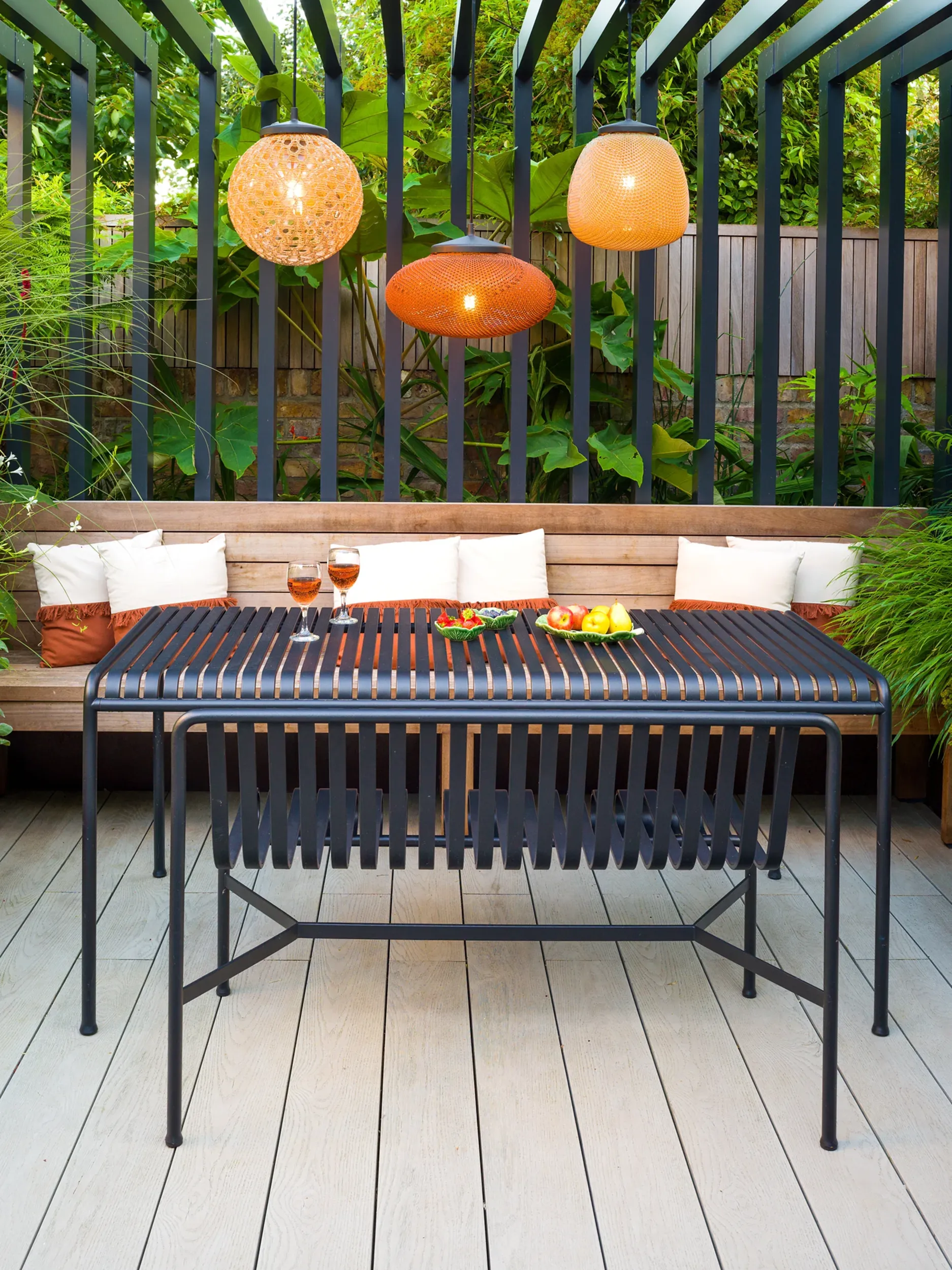 Stunning garden pergola with pendant lights and dining table, planting and deck