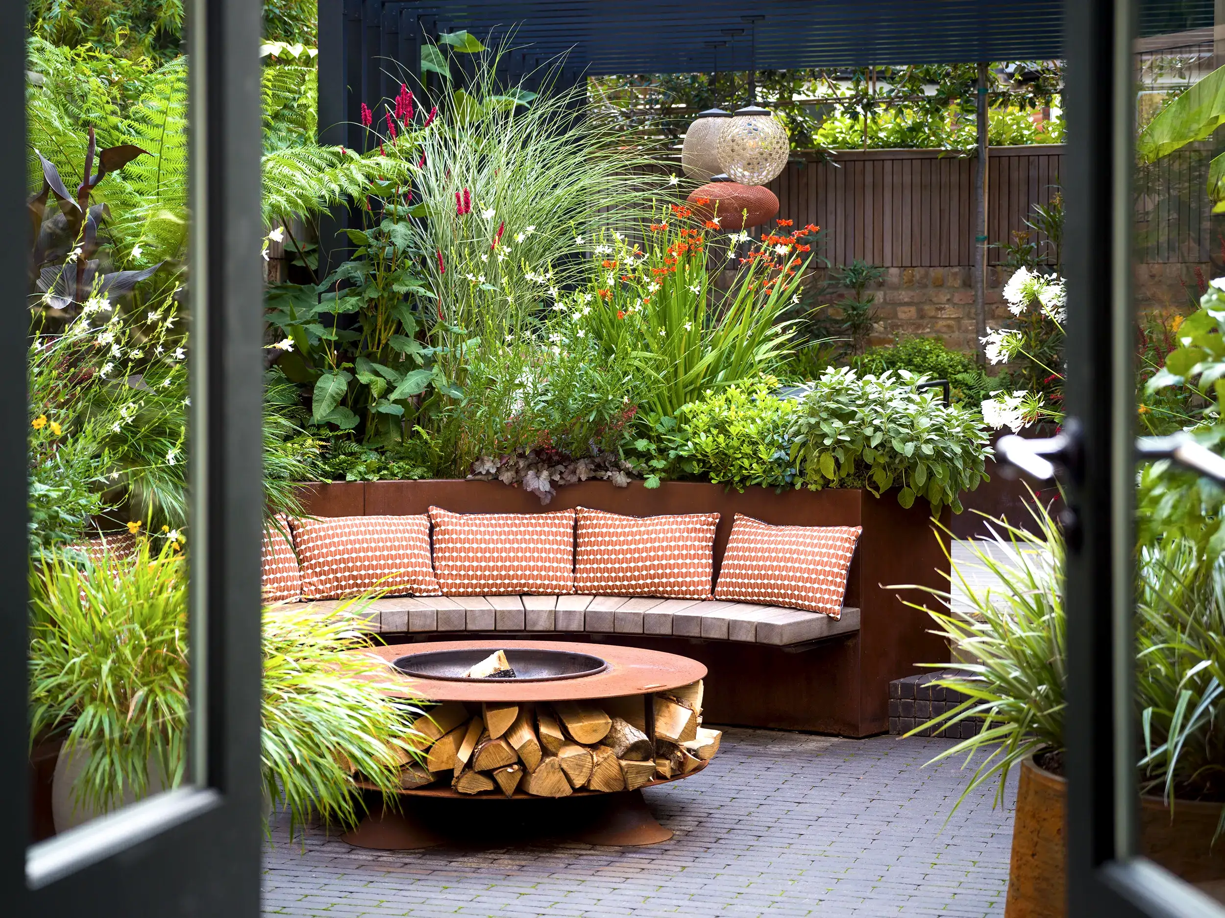 Small urban garden with seating and bench surrounding a firepit.