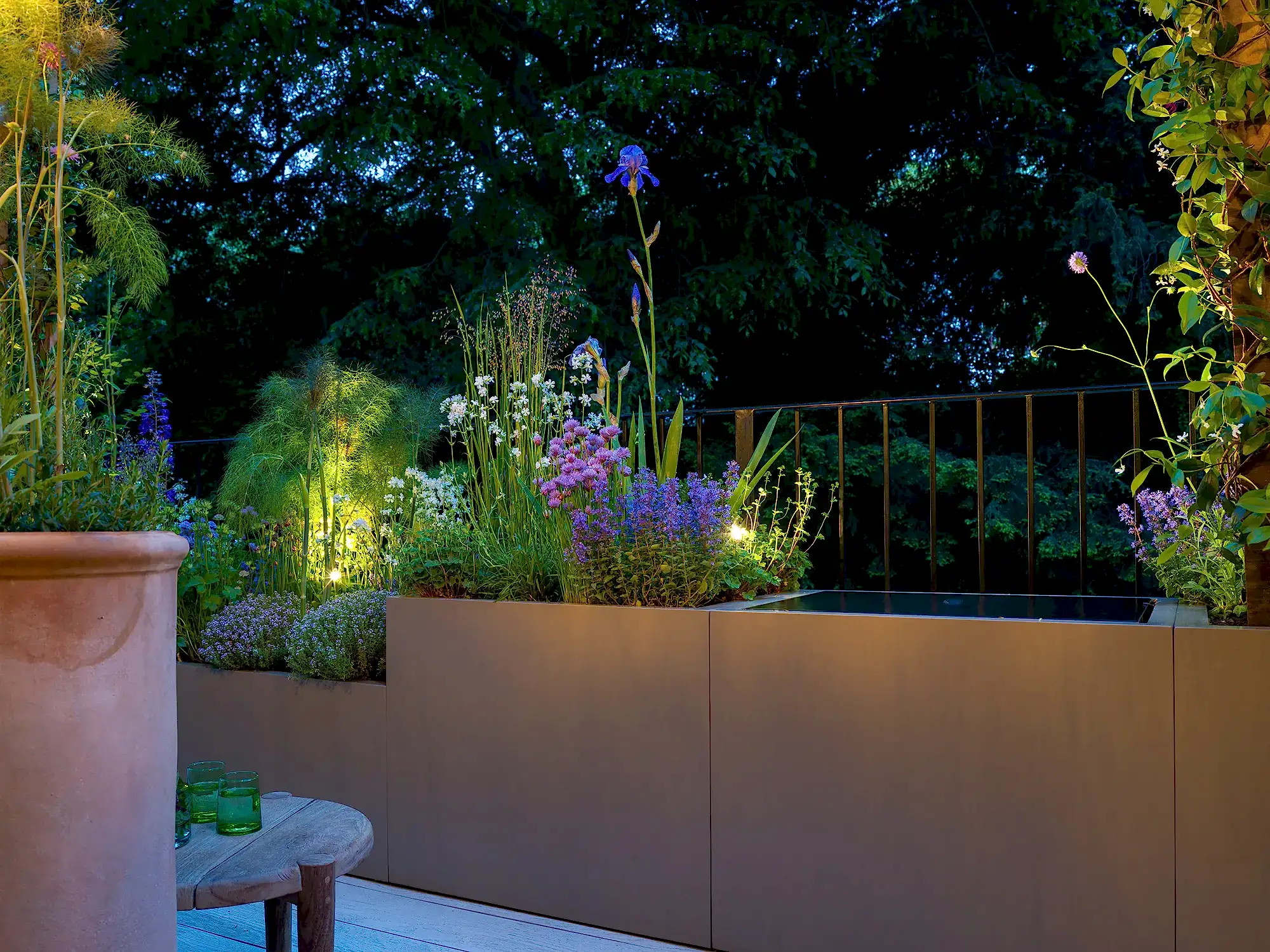 London balcony design to make a small garden in an urban space with planting, planters and water feature. Lighting design brings the space alive at night