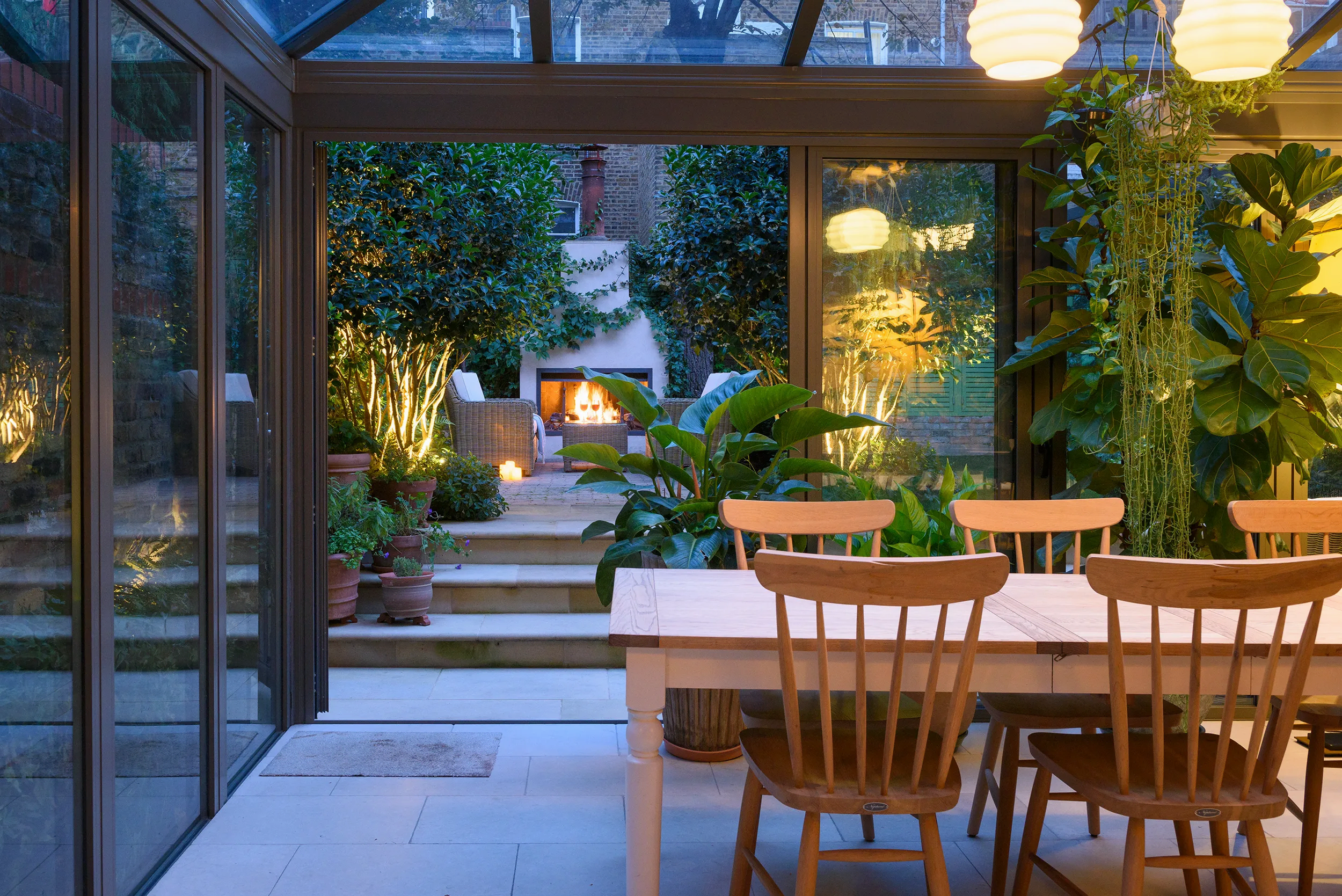 a table and chairs in a room with a fireplace and plants