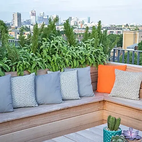 a bench with pillows and plants on it