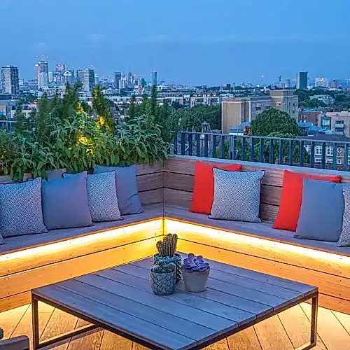 a bench with pillows on it and a table with plants on it