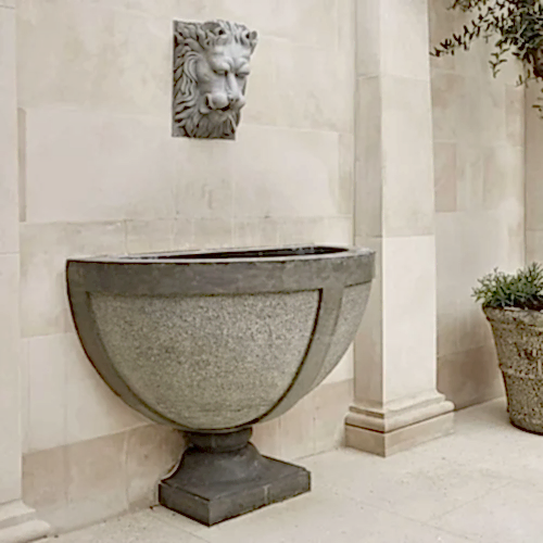 a stone bowl with a lion head on the wall