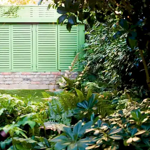 a green fence with plants and trees