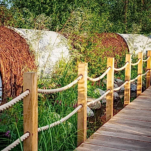 a wooden walkway with rope fence and a roll of hay