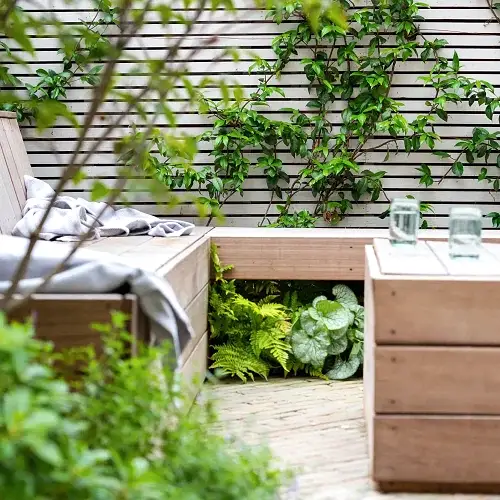 a wooden bench and table with plants on the side