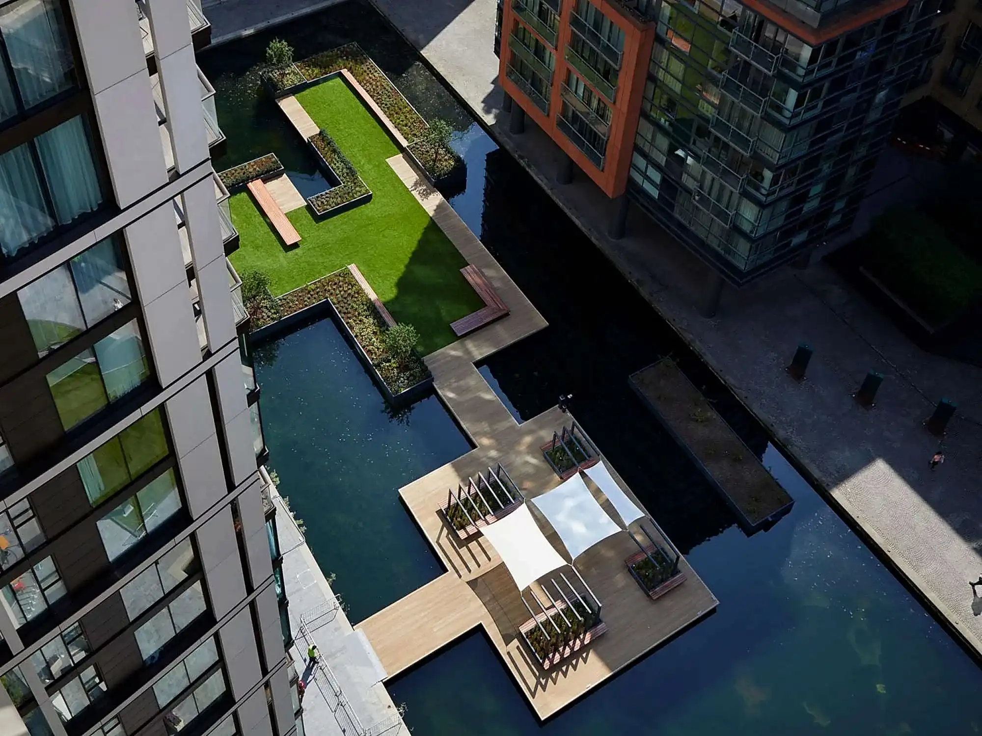 a small pool with a small patio and a small lawn in the middle of a city